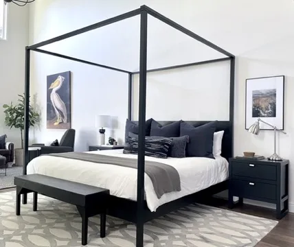 Primary bedroom near the American River in Sacramento with black canopy bed and gallery wall by Designed Curated