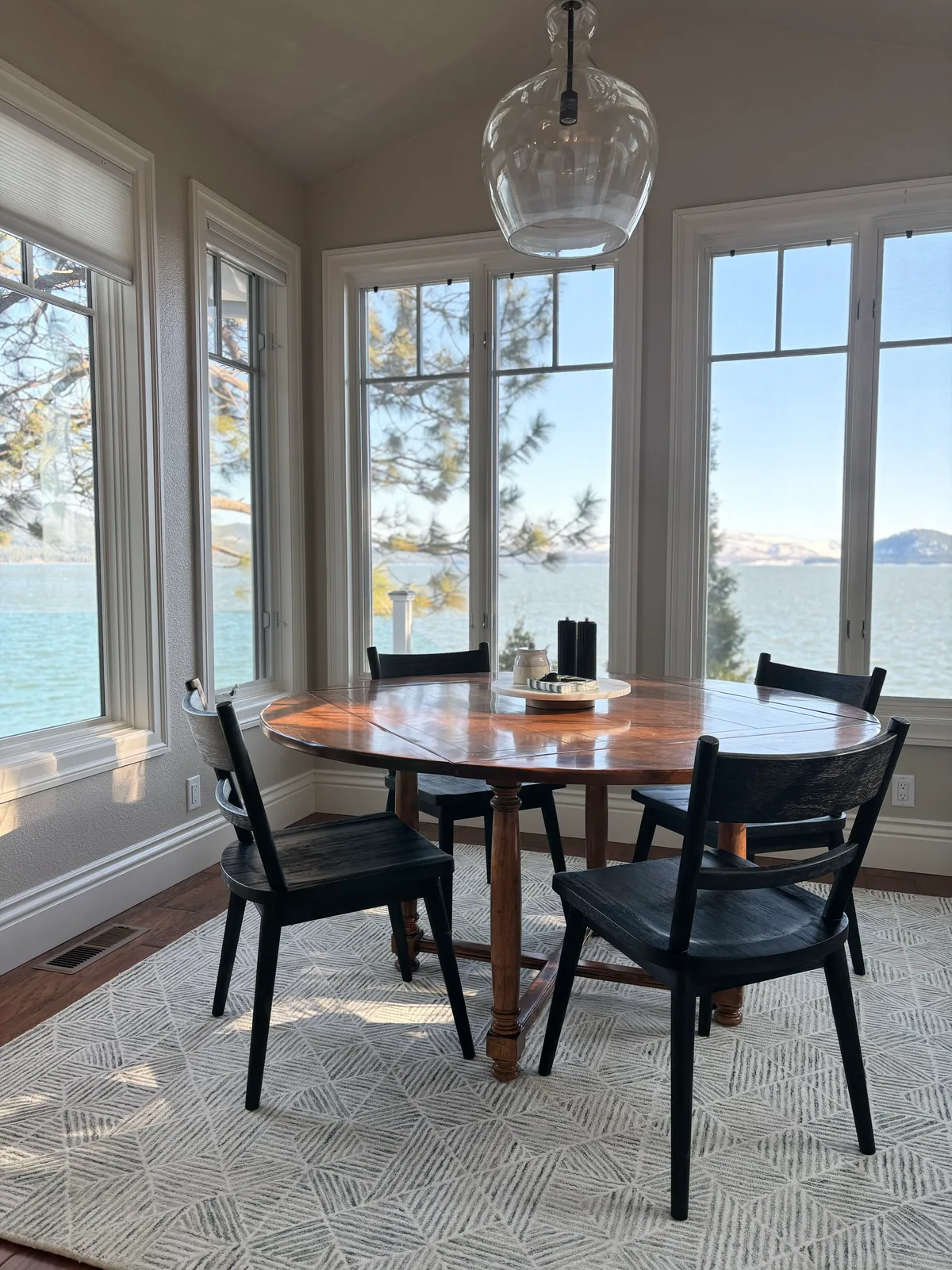 Lakefront dining nook in a Lake Almanor vacation home with panoramic windows and walnut table by Designed Curated
