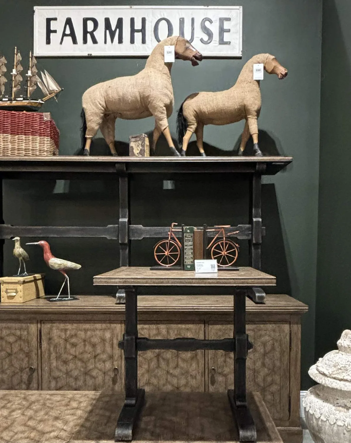 A farmhouse style interior display featuring decorative horse sculptures, a wooden table, and various rustic decor items