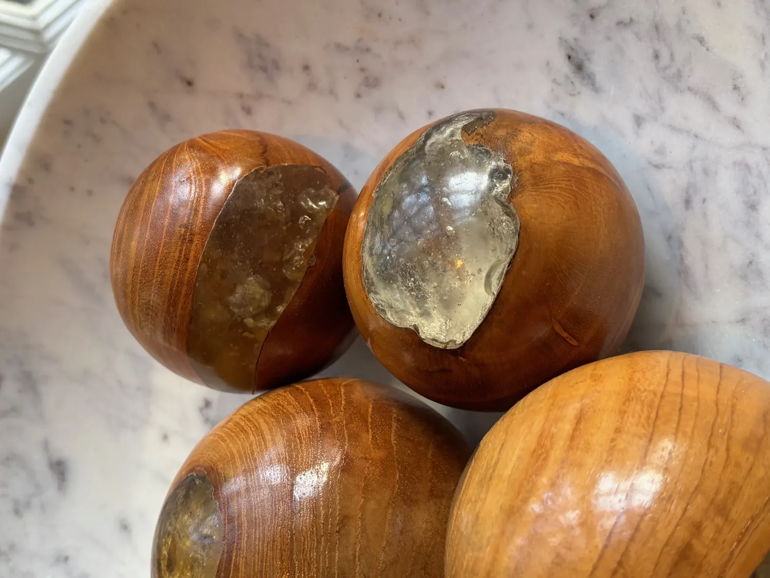 Close-up of four wooden spheres with resin inlays on a marble surface