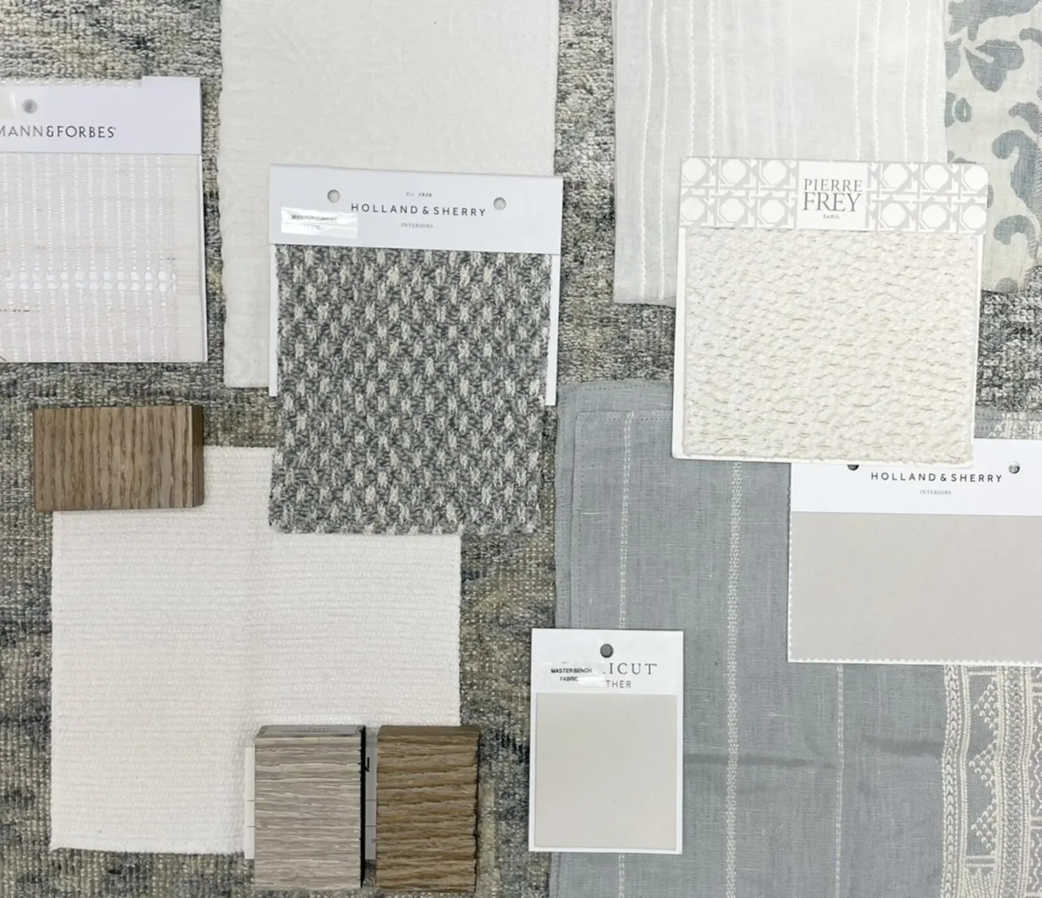 A flat lay of various fabric swatches, wood samples, and paint chips arranged on a textured surface