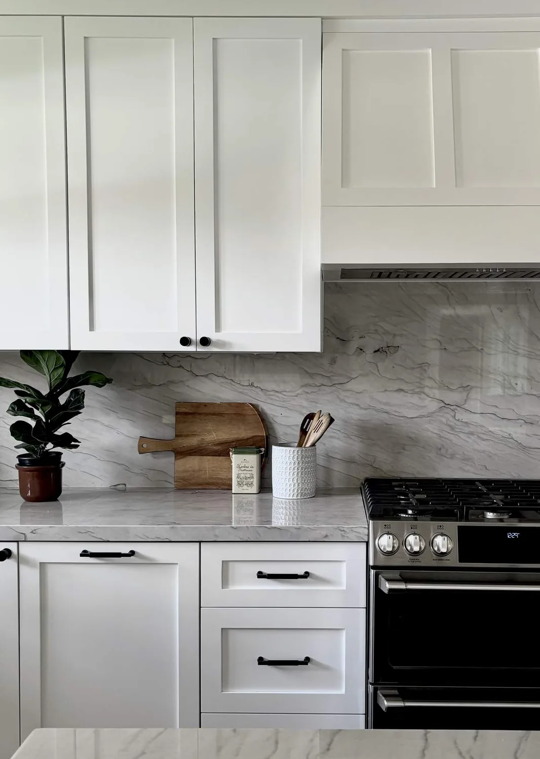 A modern kitchen with white marble countertops, blue velvet chairs, and gold accents