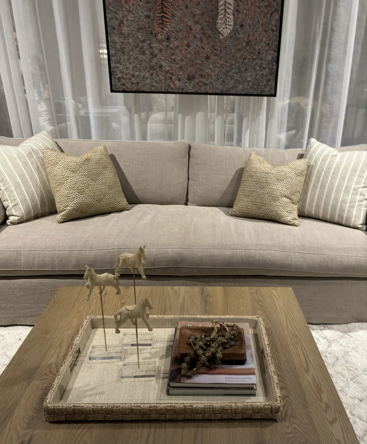 A beige sofa with textured and striped pillows in a living room setting, with a wooden coffee table holding a woven