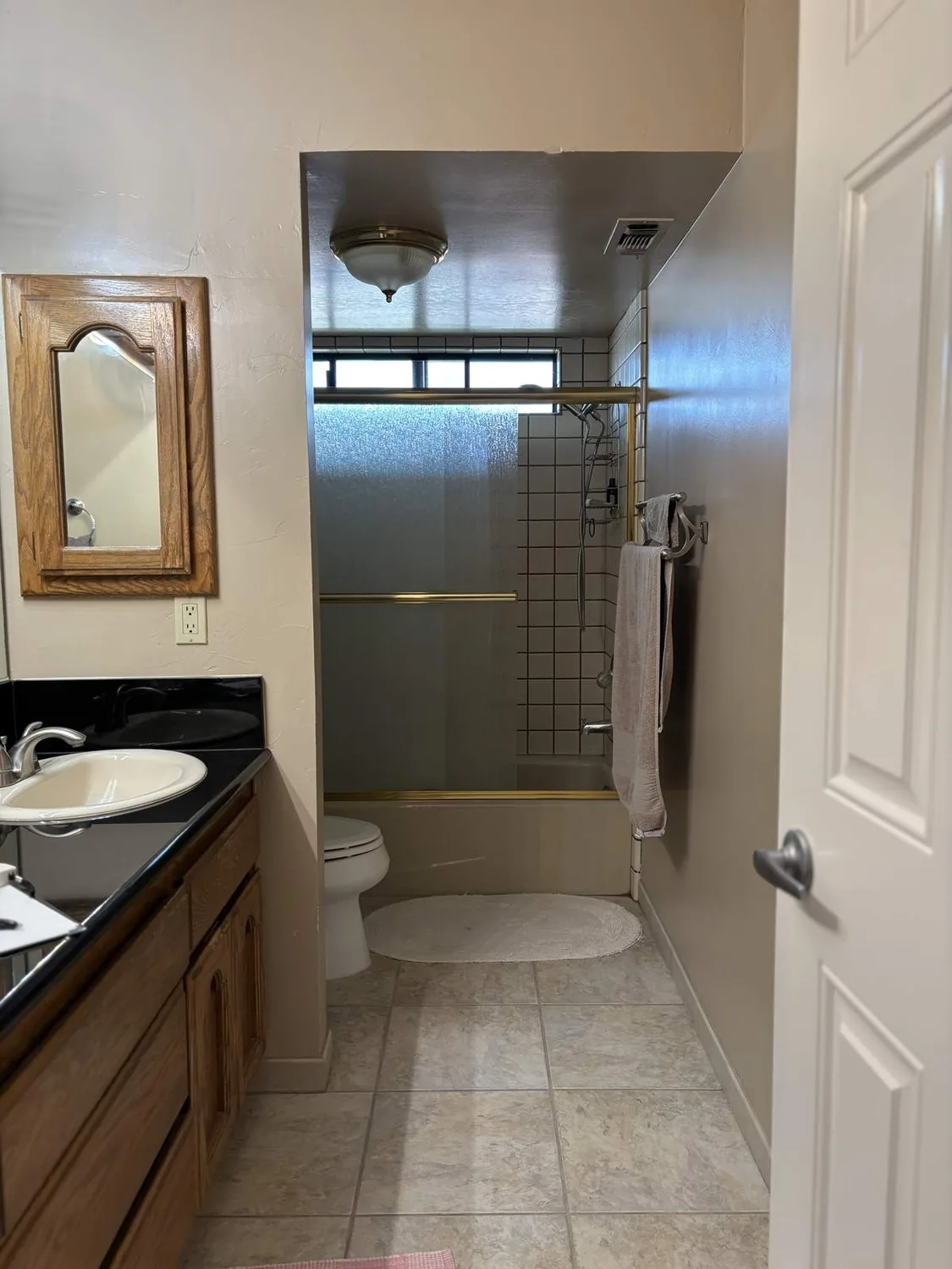 A kitchen with wooden cabinets and countertops taped off for painting or renovation, with a drop cloth on the floor