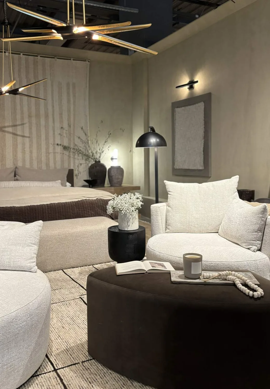 A cozy bedroom and living area with neutral tones, modern lighting, and textured furnishings