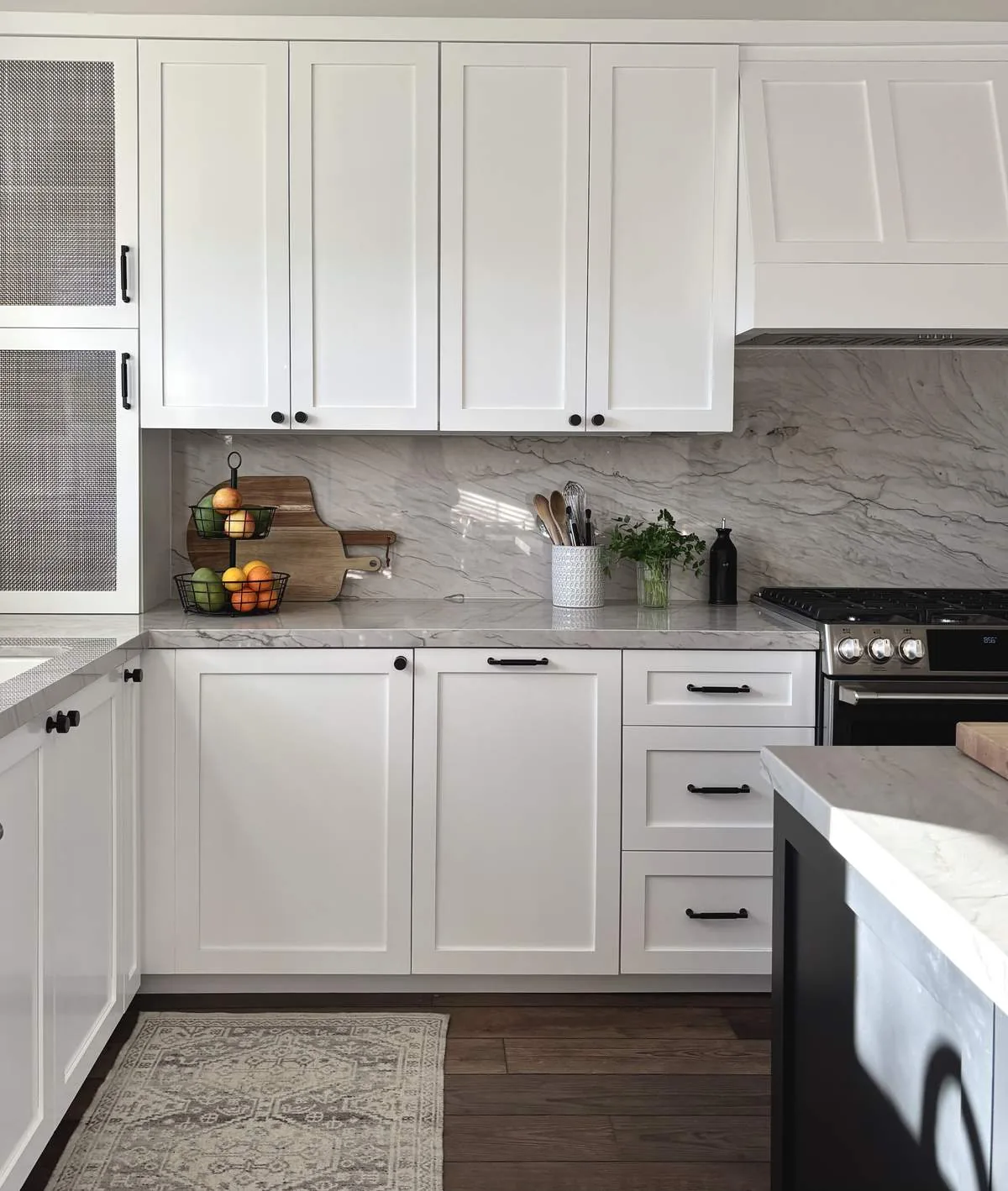 White cabinets with marble tops. A backsplash and a gas stove. Wood floors finish the job