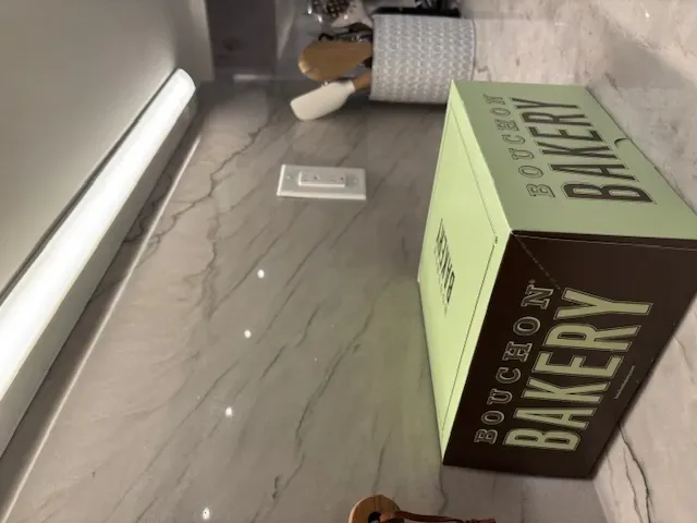 A kitchen countertop with a light fixture above, a utensil holder, and a Bouchon Bakery box